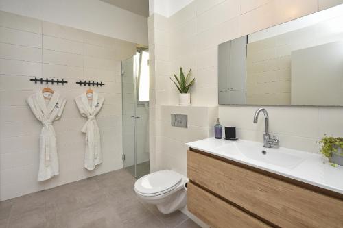 a white bathroom with a toilet and a sink at THE ALTA GALILEA - 2BRM WITH POOl/Amazing view/Gakuzi in Mishmār Hāyardin