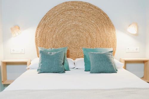 1 cama con cabecero de mimbre y almohadas azules en Apartamentos Los Flamencos, en Daimiel