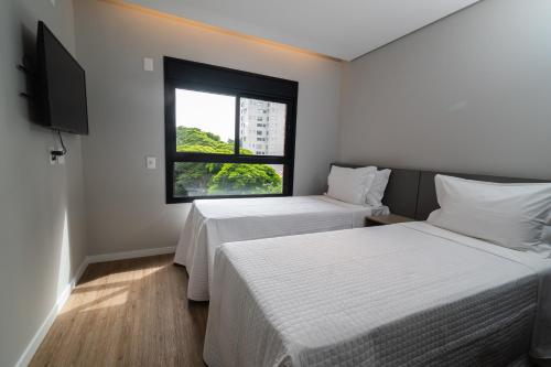 two beds in a room with a window at EZ Moema Hotel in Sao Paulo