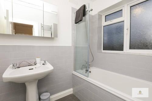 a white bathroom with a sink and a mirror at Modern 4-Bedroom 2-Bathroom with Off Road Parking in Great Sankey by Amazing Spaces Relocations Ltd in Great Sankey