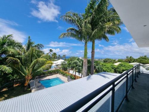 d'un balcon avec une piscine et des palmiers. dans l'établissement Villa Fleur de Coco - 8p. - piscine privée - haut standing, à Saint-Pierre