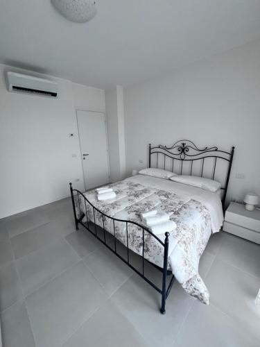 een witte slaapkamer met een bed met een zwart frame bij Casa vacanze Sofy & Marty in Cattolica