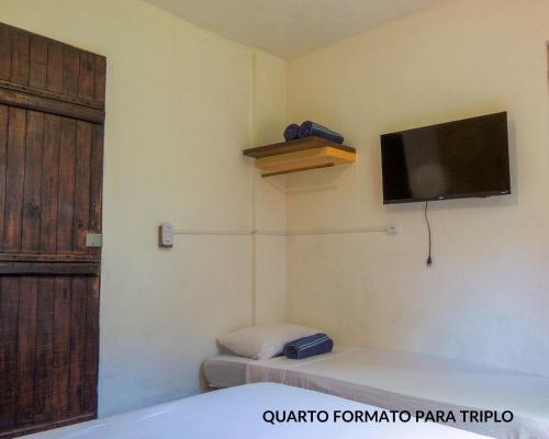 um quarto com uma televisão na parede e uma cama em Recanto da Floresta Suites em Ubatuba