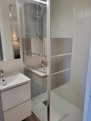 een witte badkamer met een douche en een wastafel bij residence du mail in Cap d'Agde