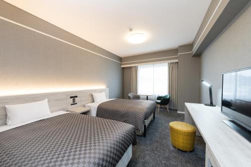 a hotel room with two beds and a flat screen tv at The One Five Garden Kurashiki - Vacation STAY 40174v in Kurashiki