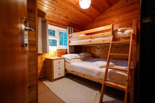 Ffestiniog的住宿－Rural Log Cabin Retreat near Coed y Brenin by Seren Short Stays，小木屋内一间卧室配有双层床