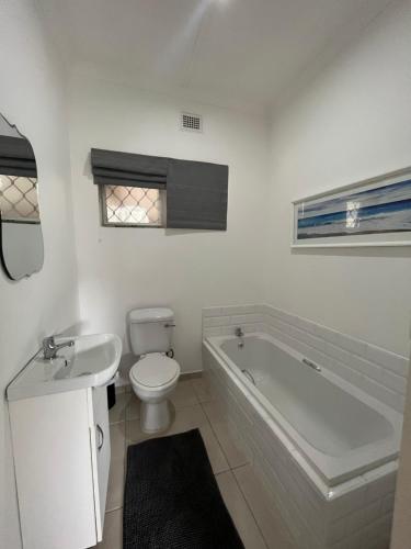 a bathroom with a tub and a toilet and a sink at Pompano Corner in Richards Bay