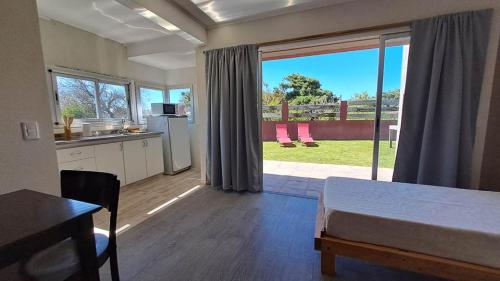 1 dormitorio con 1 cama y cocina con ventana grande en Apart Costa Mediterránea en Villa Gesell