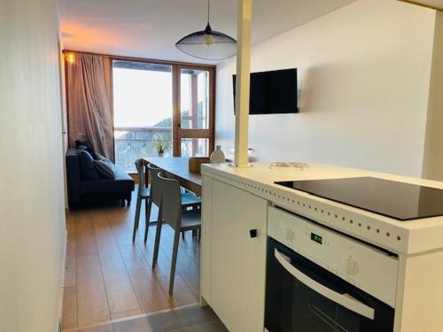 une cuisine et une salle à manger avec une table et un comptoir dans l'établissement Appartement 3 pièces rénové, face Mont-Blanc, ski aux pieds, balcon, proche centre station - FR-1-346-529, à Arc 2000