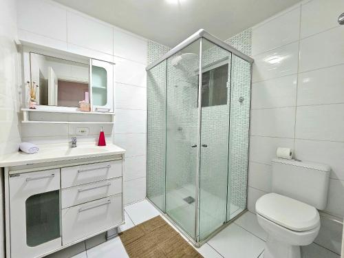a white bathroom with a shower and a toilet at Apt Centro de Foz, para até 8 pessoas com garagem in Foz do Iguaçu