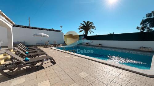 a swimming pool with lounge chairs next to a building at Villa Bea by Sunny Deluxe in Albufeira