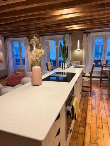 une grande cuisine avec des comptoirs blancs et des fenêtres dans l'établissement Appartement luxe Louvre Paris, à Paris