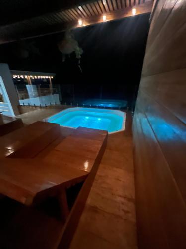 a swimming pool in a dark room with a wooden table at PUNTA VELEROS ROOFTOP in Los Órganos