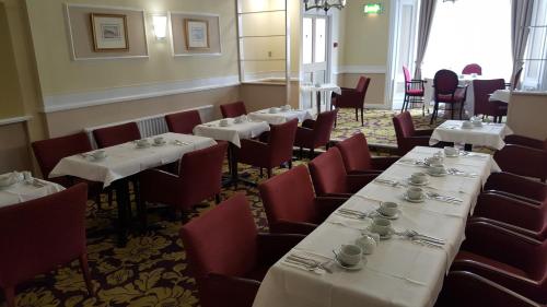 a dining room with white tables and red chairs at Maison Gorey Hotel in Grouville