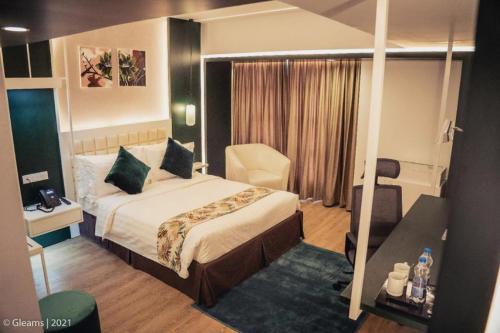 ラジシャヒにあるGrand River View Hotel - Rajshahiのベッドと椅子のあるホテルの部屋
