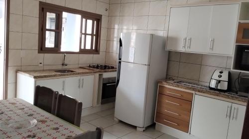 una cucina con armadietti bianchi e frigorifero bianco di Casa de praia a Florianópolis