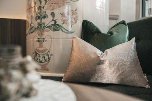 a couch with two pillows and a vase at Garni Hotel Miara - Your Dolomites Home in Selva di Val Gardena