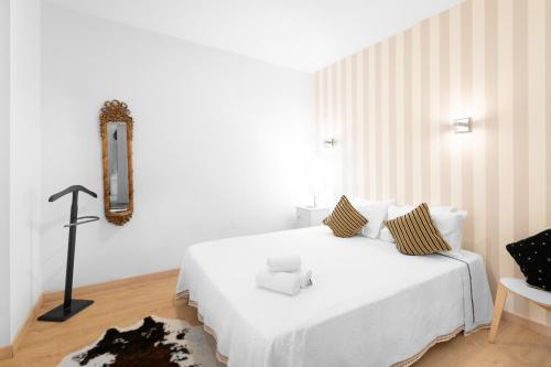 a white bedroom with a white bed and a chair at Ínsua Hostel in São Pedro do Sul