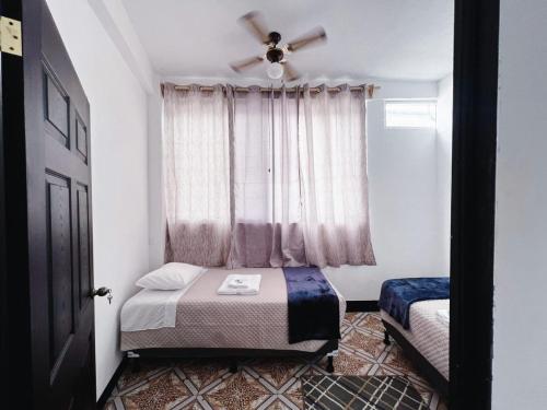 a bedroom with a bed and a window with a fan at Apartamento en la zona viva con parqueo exclusivo in San Pedro La Laguna