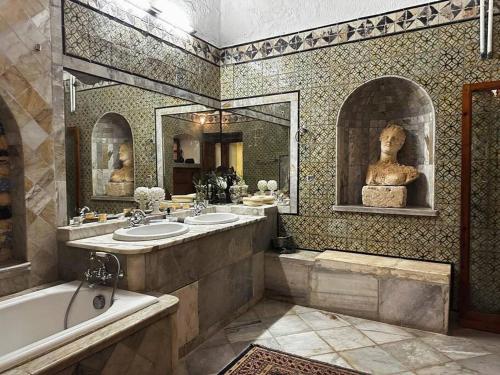 uma casa de banho com 2 lavatórios e uma banheira e uma estátua em Suite Noor B&B Pool SidiBouSaid em Sidi Bou Saïd