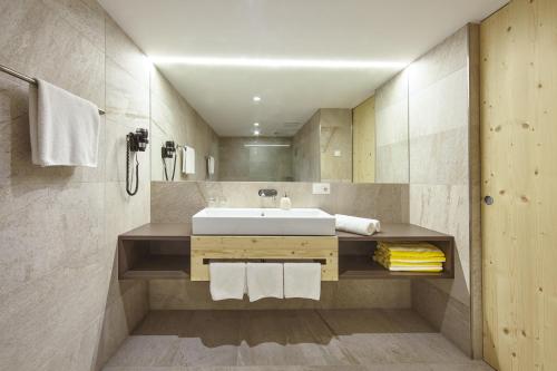 een badkamer met een wastafel en een spiegel bij Hotel Obermoosburg in Coldrano