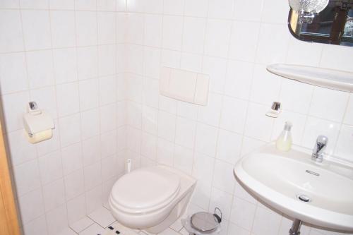 a white bathroom with a toilet and a sink at Haus Bergwelt in Grän
