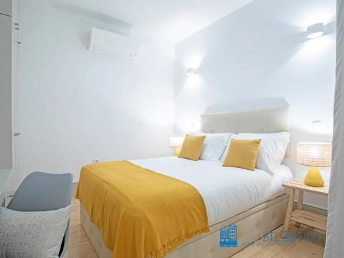 een slaapkamer met een bed met gele lakens en een stoel bij Porto Almada Design Loft in Porto