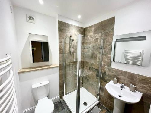 uma casa de banho com um chuveiro, um WC e um lavatório. em London Modern Flat near transports em Londres