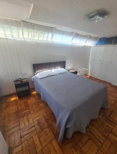 una camera con un grande letto e un pavimento in legno di Las condes, Amplia habitación con baño privado a Santiago