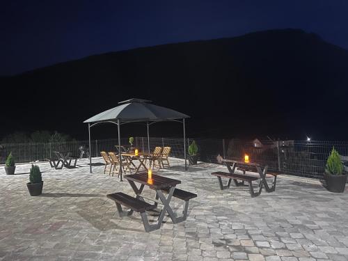 a group of picnic tables with an umbrella at night at Mavrovo Square One Bedroom APARTMENT in Mavrovo
