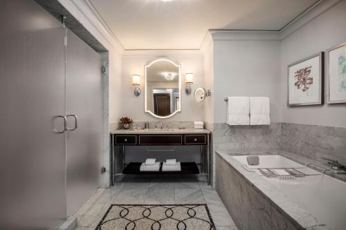 a bathroom with a tub and a sink and a mirror at Waldorf Astoria Chicago in Chicago