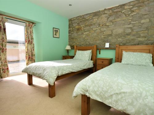 2 Betten in einem Zimmer mit einer Steinmauer in der Unterkunft 4 Bed in Whaley Bridge PK534 in Whaley Bridge