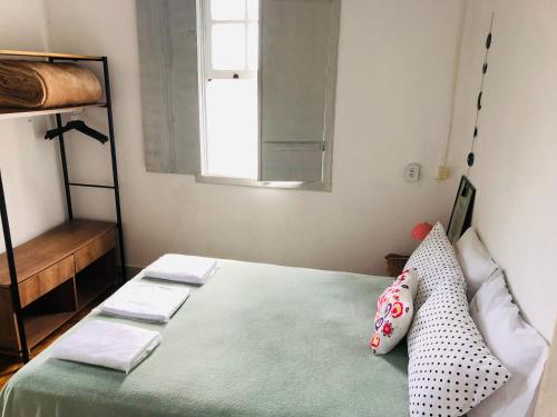 a bedroom with a bed with pillows and a window at Ouro Preto Hostel in Ouro Preto