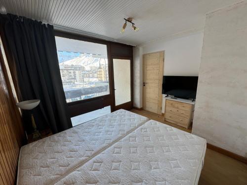 um quarto com uma cama e uma grande janela em Appartement Tignes - Quartier Calme - 2 chambres - 3 Télévisions - Netflix & Wifi inclus em Tignes