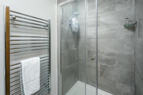 a bathroom with a shower with a glass door at The Coach House in Bamburgh