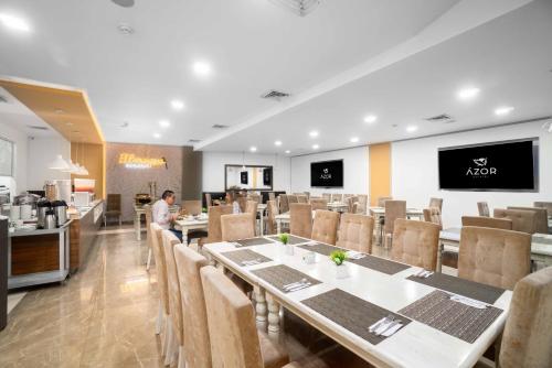 a restaurant with tables and chairs and a man in the background at Azor Hotel Cali Versalles in Cali