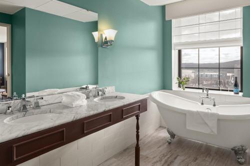 a bathroom with two sinks and a tub and a window at Landmark Inn in Marquette