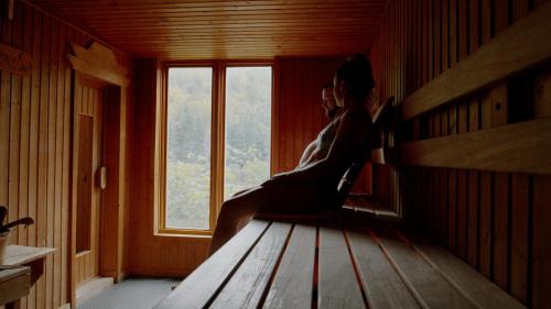 a woman sitting on a bench in a room with a window at Nordique spa Stoneham in Stoneham
