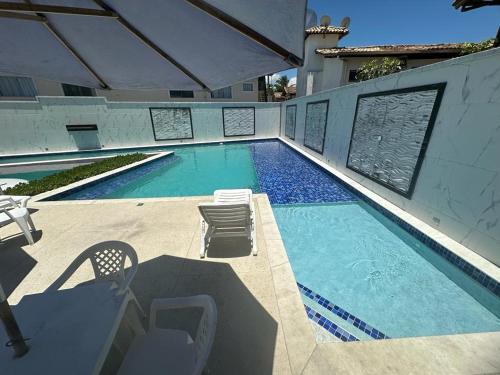 a swimming pool with two chairs and a table and chairs at Apartamento Porto Villa dos Diamantes 22 in Porto Seguro