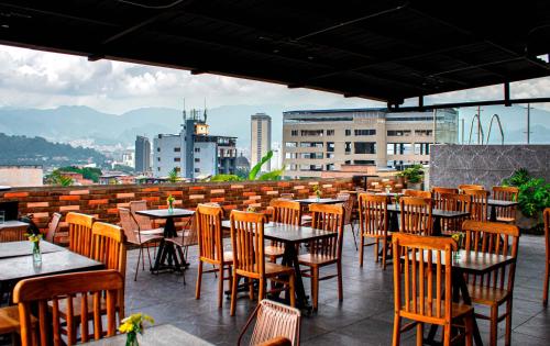 un restaurante con mesas y sillas en la azotea en Apartahotel Medellin en Medellín