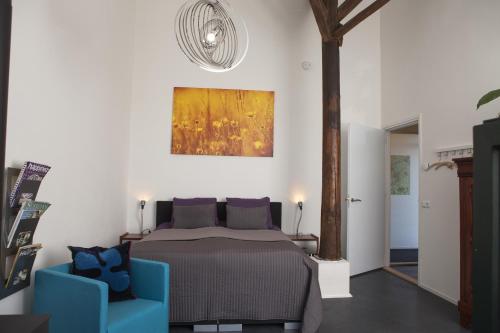 um quarto com uma cama e duas cadeiras azuis em Logement de Kaap em Terheijl