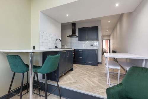 a kitchen with blue cabinets and green chairs at Ettie's in Blackpool