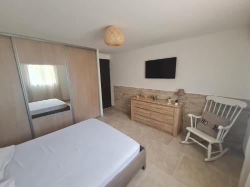 a bedroom with a bed and a chair and a television at Appartement Vacances ZEN in Fréjus