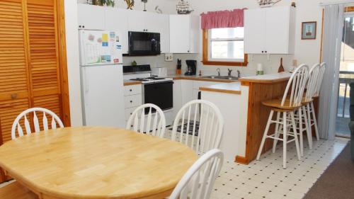 a kitchen with a wooden table and white appliances at Semi-Oceanfront, Close to Beach Access, KD240, The Ocean Winds in Kill Devil Hills