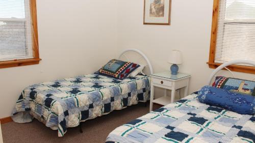 a bedroom with two beds and a nightstand with a bed and a table at Semi-Oceanfront, Close to Beach Access, KD240, The Ocean Winds in Kill Devil Hills