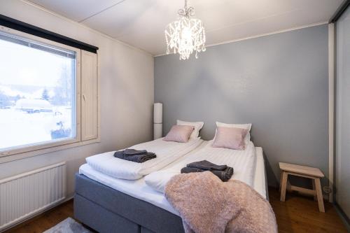 una camera da letto con un letto con un lampadario a braccio e una finestra di Arctic River House a Rovaniemi