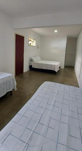 a large room with two beds and a large tiled floor at Pousada Esmeralda in Maragogi