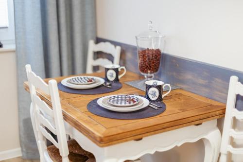 a wooden table with plates and mugs on it at APARTEMENTY ''WERANDA'' z ogrodem w centrum in Kudowa-Zdrój