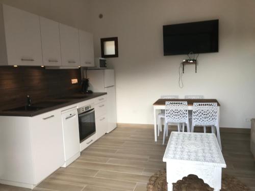 a kitchen with white cabinets and a table with chairs at Gîte A Funtana Montestremo, Balagne, Haute Corse in Manso