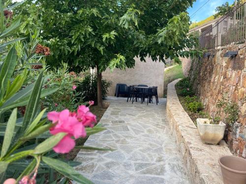a stone walkway with a table and chairs in a garden at Gîte A Funtana Montestremo, Balagne, Haute Corse in Manso